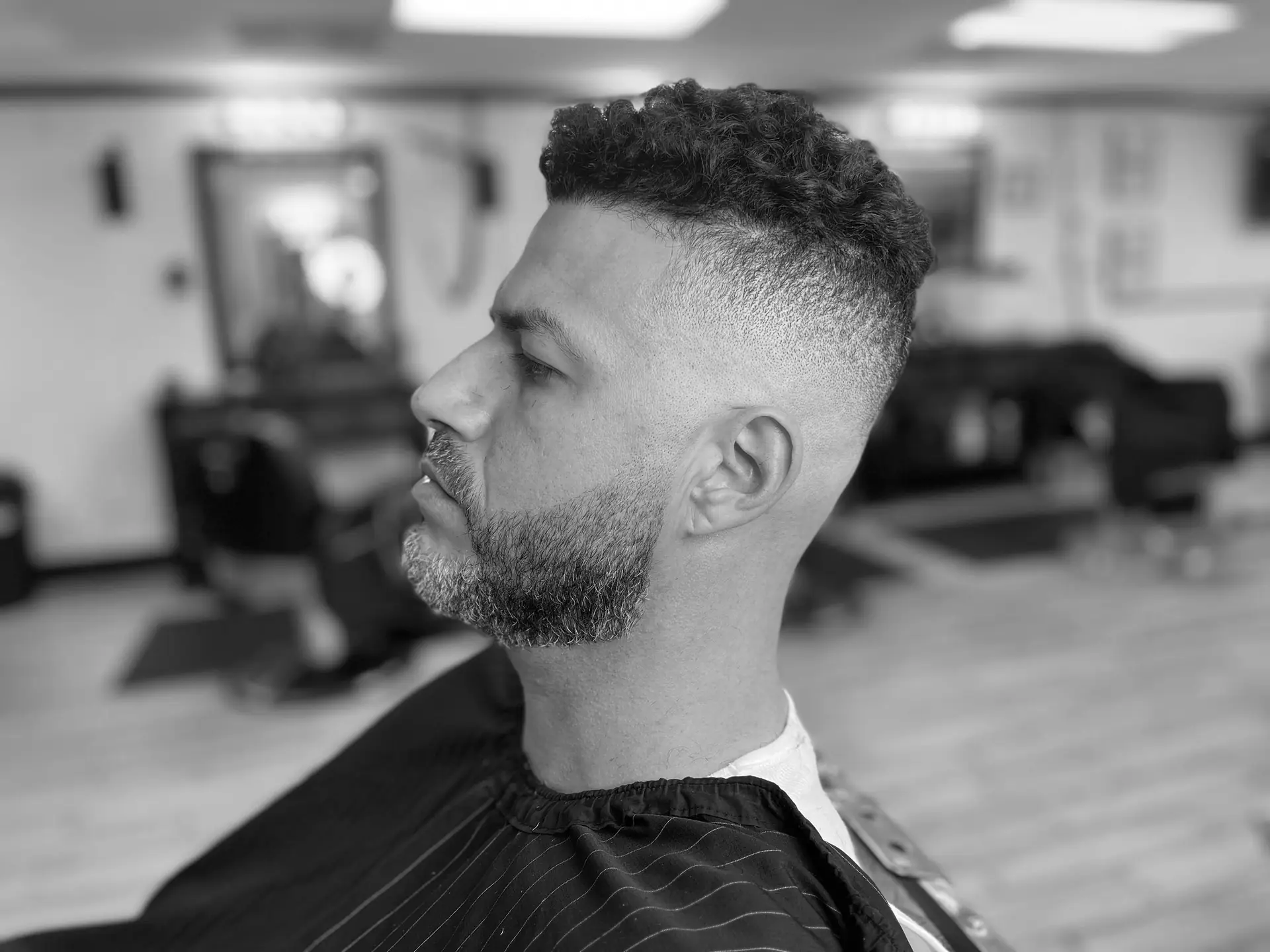 Client with a fresh skin fade and trimmed beard in the barber chair at Crispy Clean Cuts